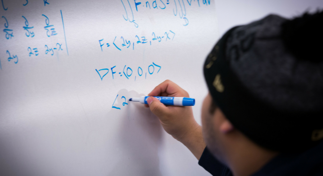 student writing math equations on a white board