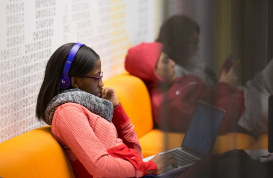 female student sitting on a couch typing on laptop